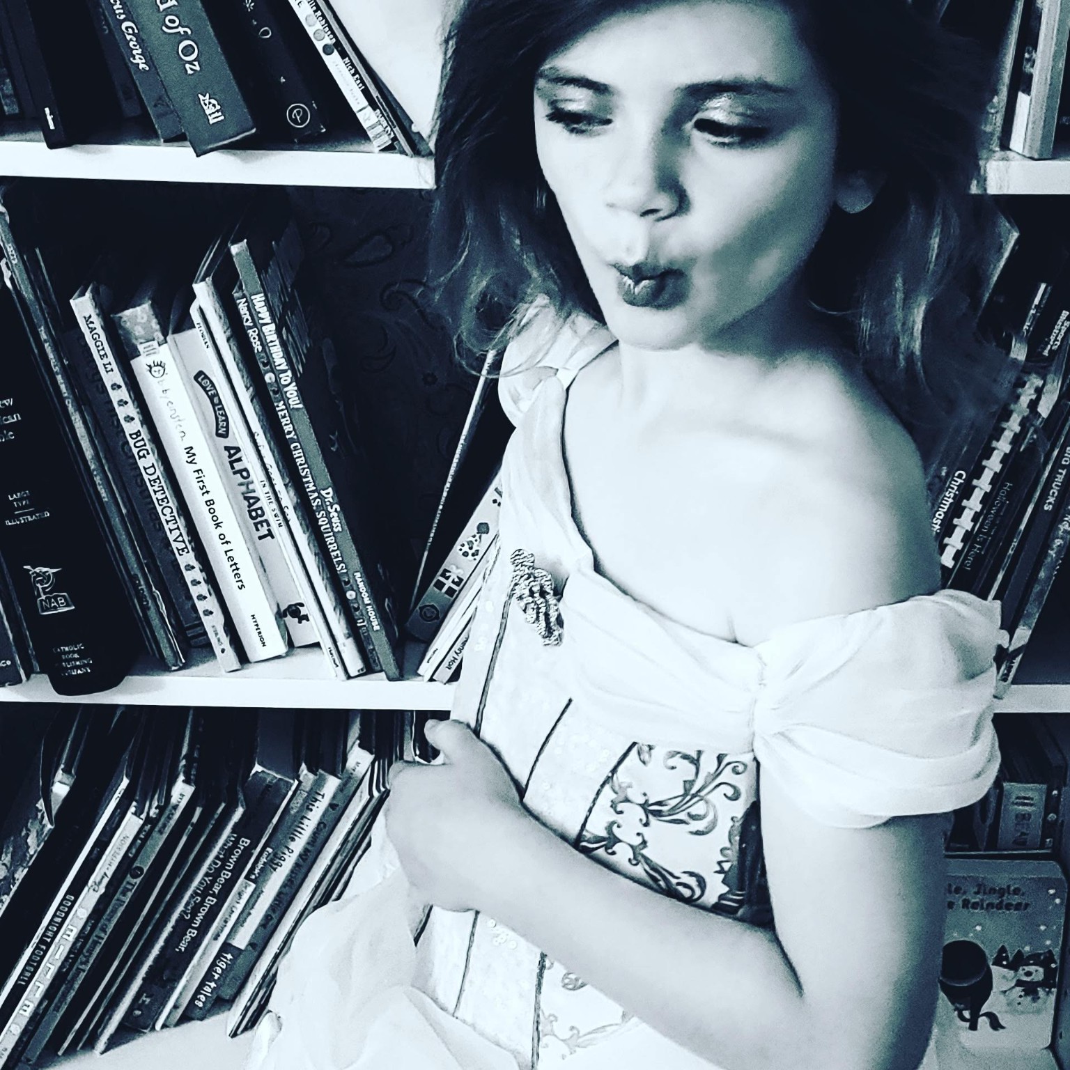 Black and white expressive portrait beside a bookshelf